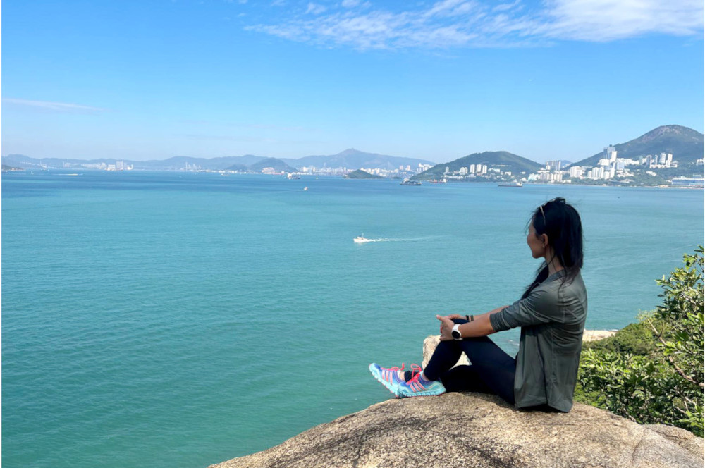 Sharon sitting on a rock looking out at the ocean